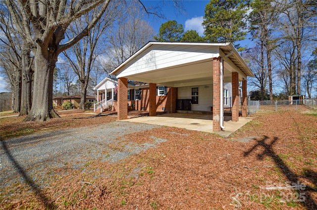 rear view of house featuring brick siding, driveway, and fence