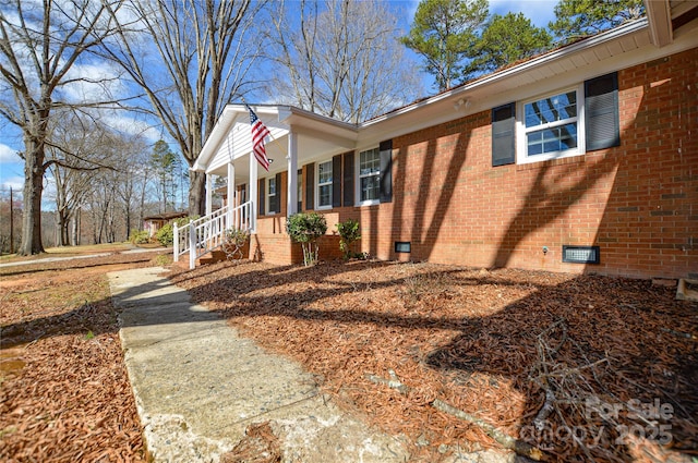 exterior space with covered porch, brick siding, and crawl space