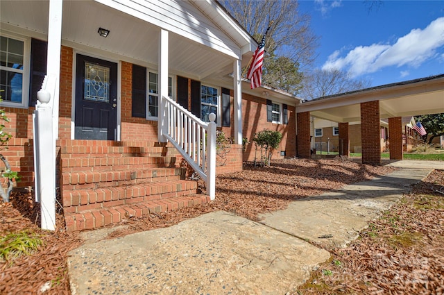 entrance to property featuring covered porch and brick siding