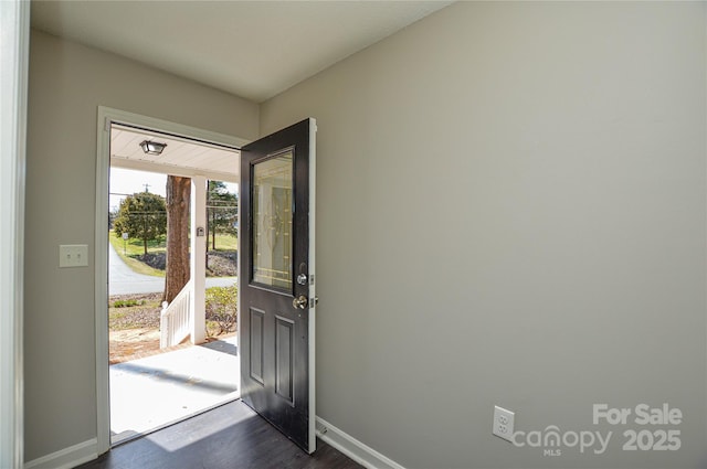 foyer entrance with dark wood finished floors and baseboards