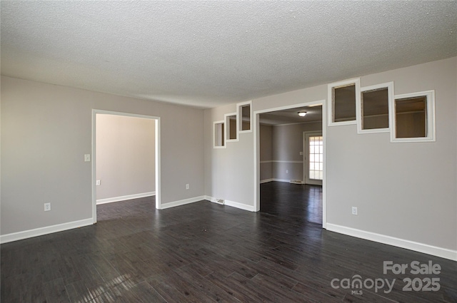 spare room with a textured ceiling, baseboards, and dark wood-style flooring