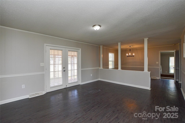 spare room featuring french doors, crown molding, dark wood finished floors, decorative columns, and visible vents