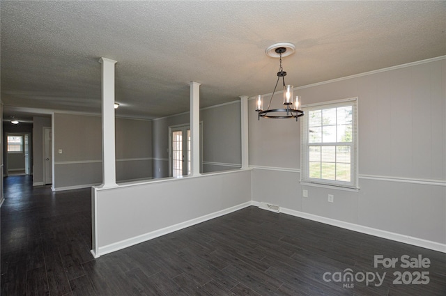 empty room with a textured ceiling, ornamental molding, and dark wood finished floors