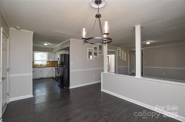 interior space featuring ornamental molding, dark wood-type flooring, a sink, a textured ceiling, and a notable chandelier