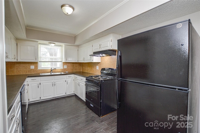 kitchen featuring under cabinet range hood, a sink, black appliances, dark countertops, and crown molding