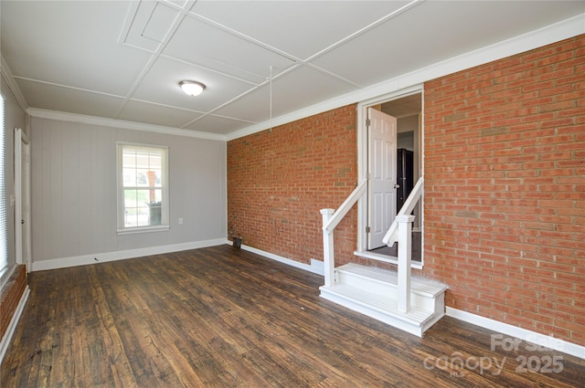 spare room featuring crown molding, brick wall, hardwood / wood-style floors, and baseboards