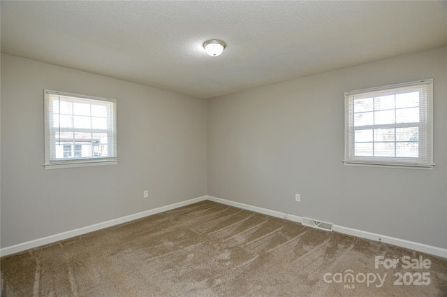 unfurnished room featuring baseboards, a textured ceiling, visible vents, and carpet flooring