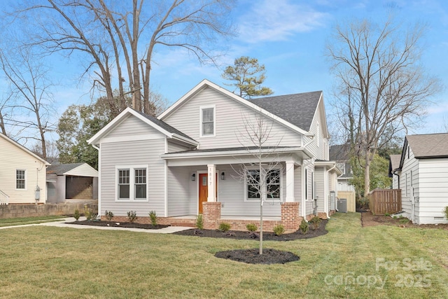 view of front facade with a shingled roof, a front yard, and fence