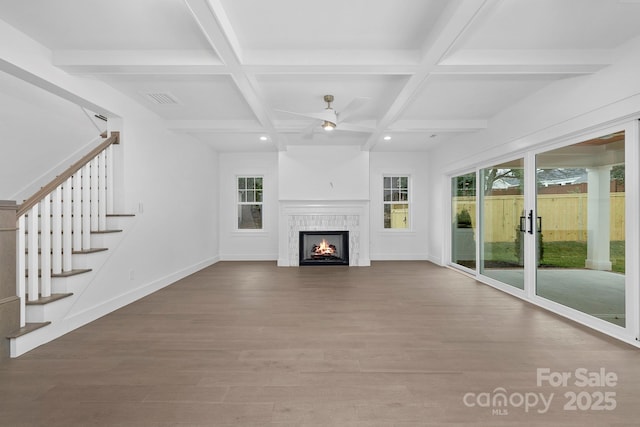 unfurnished living room featuring beamed ceiling, wood finished floors, visible vents, and baseboards