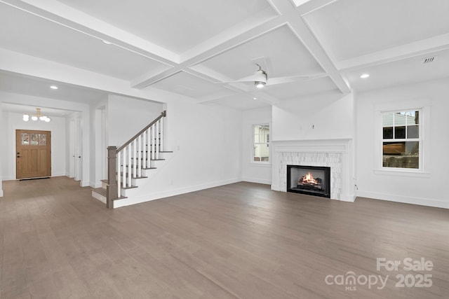 unfurnished living room featuring coffered ceiling, stairway, and wood finished floors