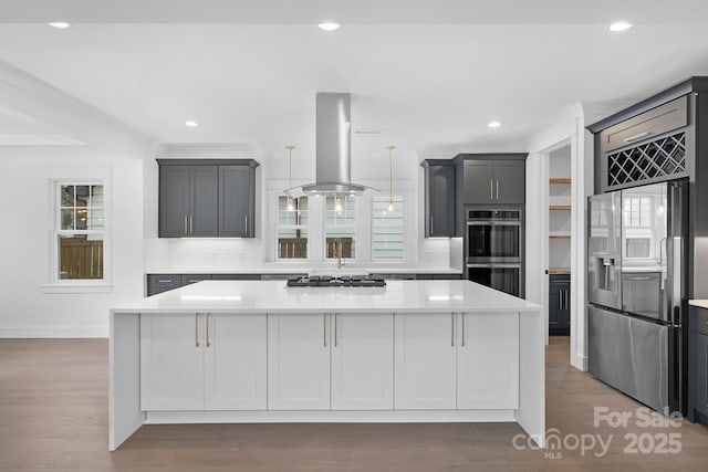 kitchen featuring stainless steel appliances, wood finished floors, a kitchen island, light countertops, and island exhaust hood