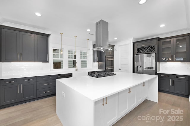 kitchen featuring island range hood, a large island, stainless steel appliances, light countertops, and light wood-type flooring