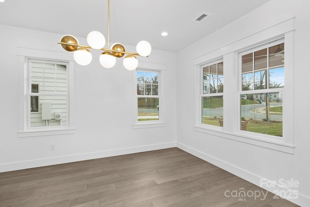 unfurnished dining area featuring baseboards, visible vents, wood finished floors, a notable chandelier, and recessed lighting