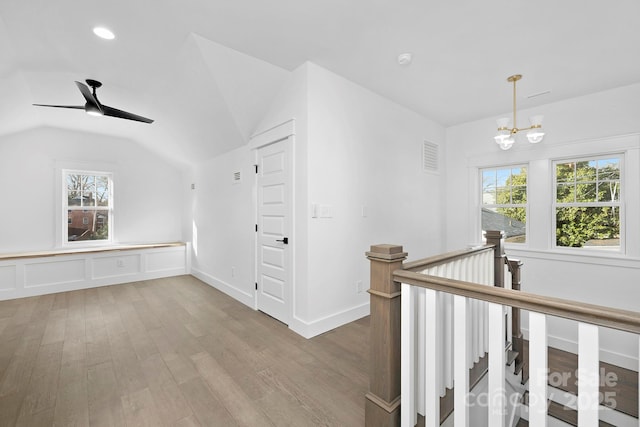 hallway featuring lofted ceiling, visible vents, an upstairs landing, wood finished floors, and a chandelier