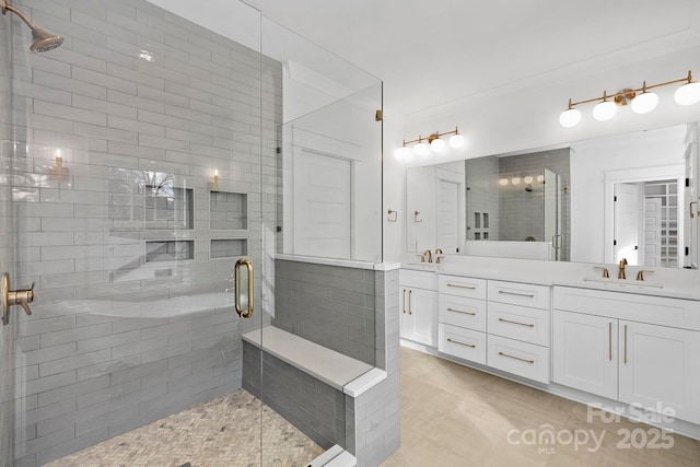 bathroom featuring crown molding, a sink, a shower stall, and double vanity