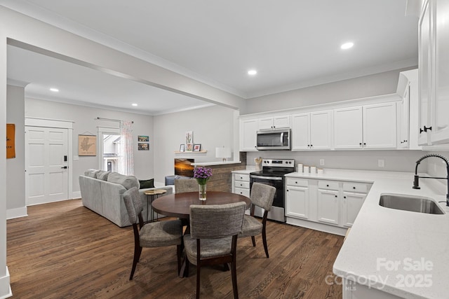 kitchen featuring dark wood-style floors, white cabinets, stainless steel appliances, and a sink