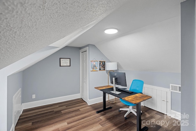 home office with visible vents, baseboards, vaulted ceiling, wood finished floors, and a textured ceiling