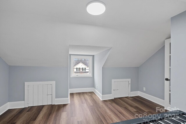 additional living space with baseboards, lofted ceiling, and wood finished floors