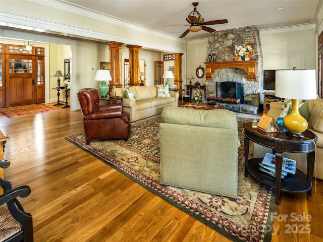 living room featuring ornamental molding, a ceiling fan, a fireplace, and wood finished floors