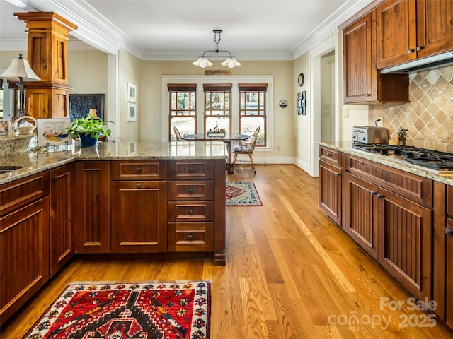 kitchen with ornamental molding, light wood-type flooring, and stainless steel gas stovetop