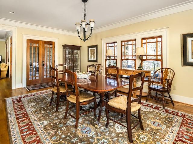 dining space with ornamental molding, french doors, an inviting chandelier, and wood finished floors