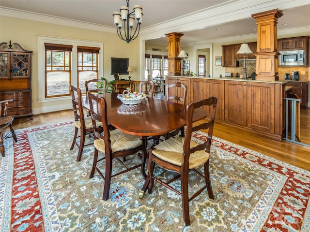 dining space with light wood-type flooring, a wealth of natural light, and ornate columns