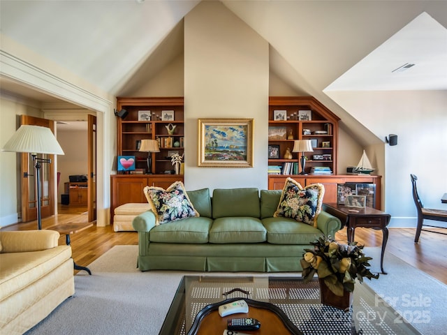 living room with lofted ceiling, baseboards, visible vents, and wood finished floors