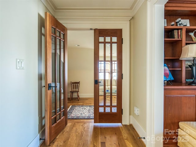 doorway to outside with light wood finished floors, french doors, ornamental molding, and baseboards