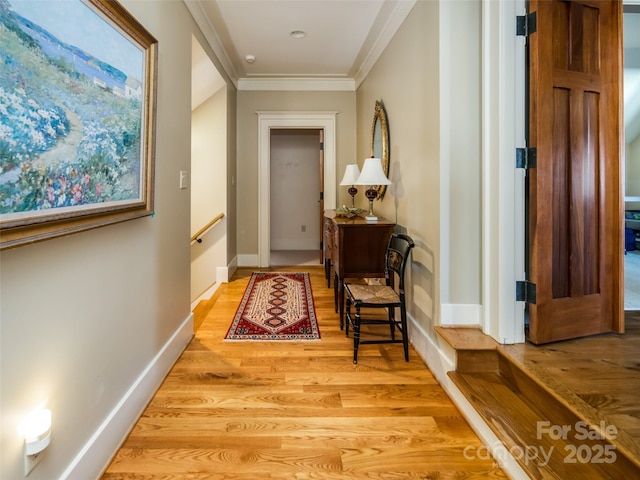 hallway with light wood-type flooring, baseboards, and crown molding