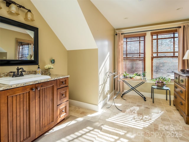 bathroom featuring lofted ceiling, baseboards, and vanity