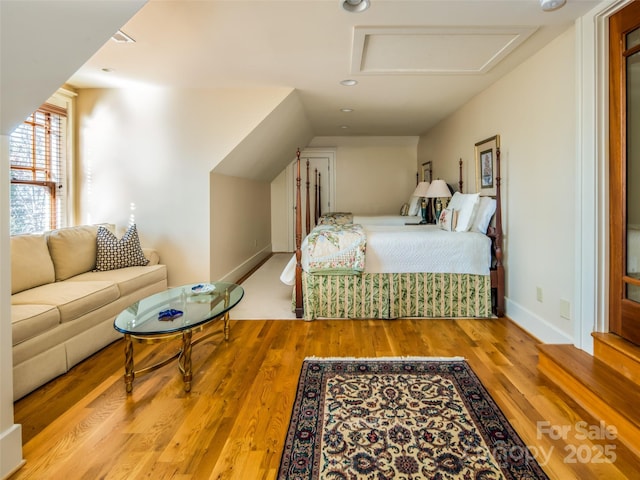 bedroom featuring attic access, baseboards, and wood finished floors