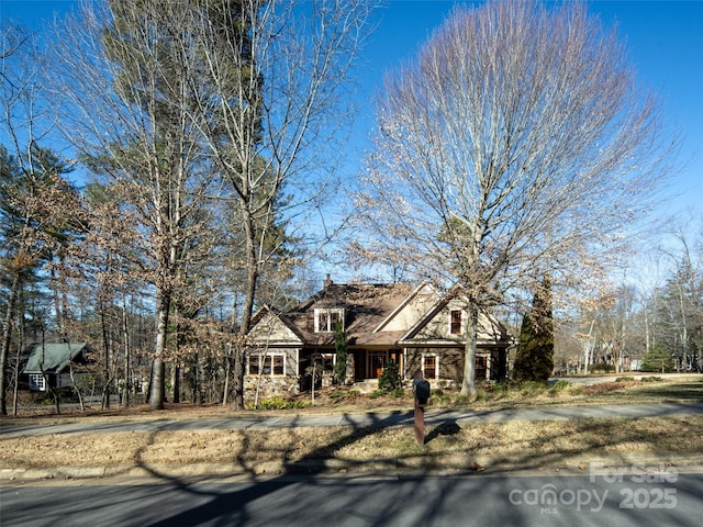 view of front of home with stone siding and a chimney