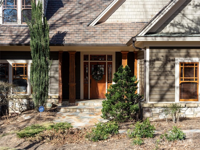 doorway to property featuring a porch, a high end roof, and stone siding