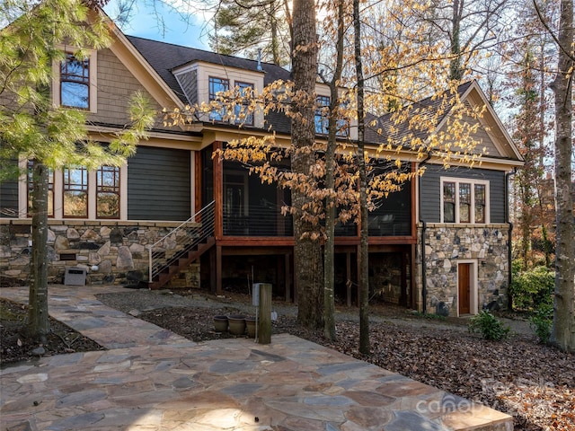 rear view of house with stone siding, stairway, and a patio