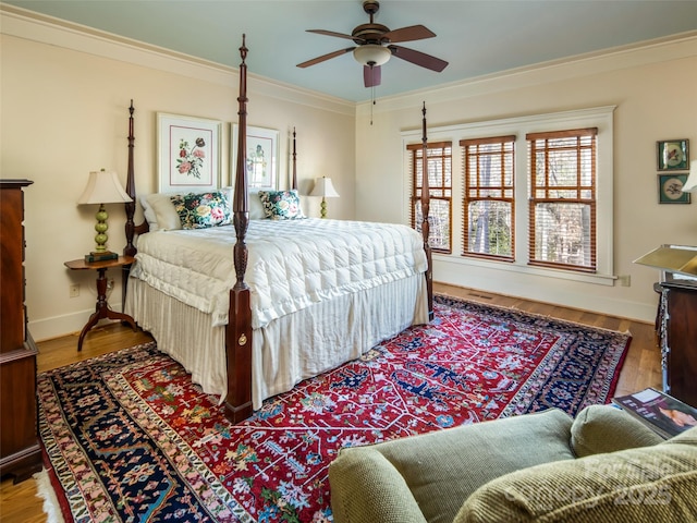 bedroom featuring ceiling fan, baseboards, crown molding, and wood finished floors