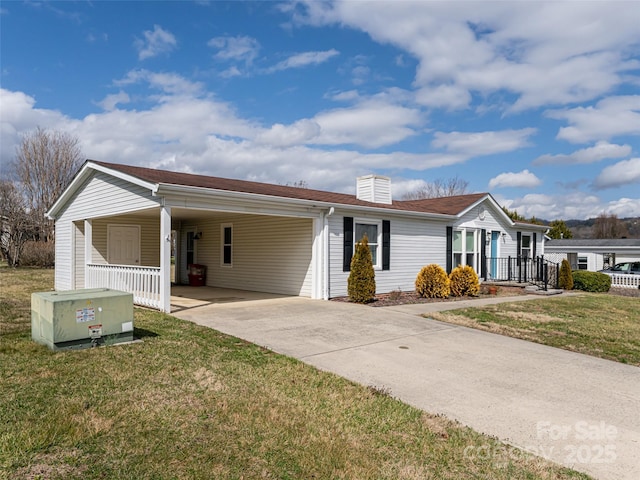 single story home featuring a carport, a chimney, concrete driveway, and a front yard