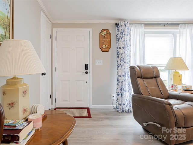 foyer entrance with light wood-style flooring, baseboards, and ornamental molding