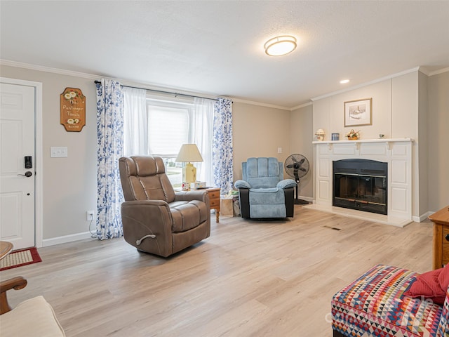 living room with a glass covered fireplace, light wood-type flooring, and ornamental molding