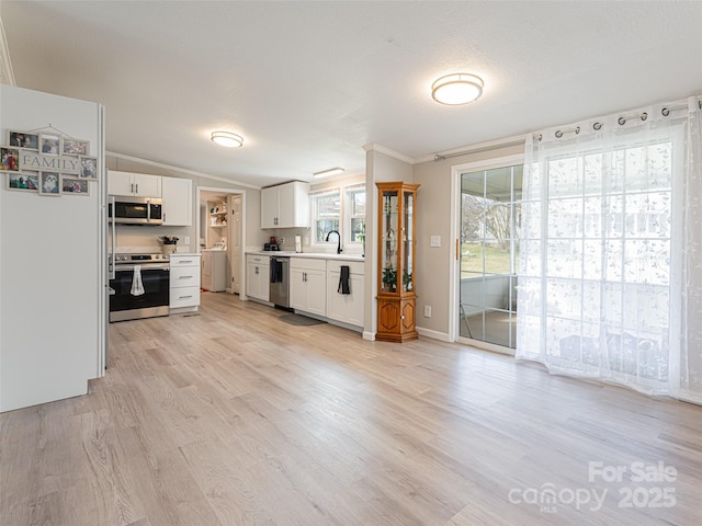 kitchen with stainless steel appliances, light countertops, white cabinets, vaulted ceiling, and light wood-style floors