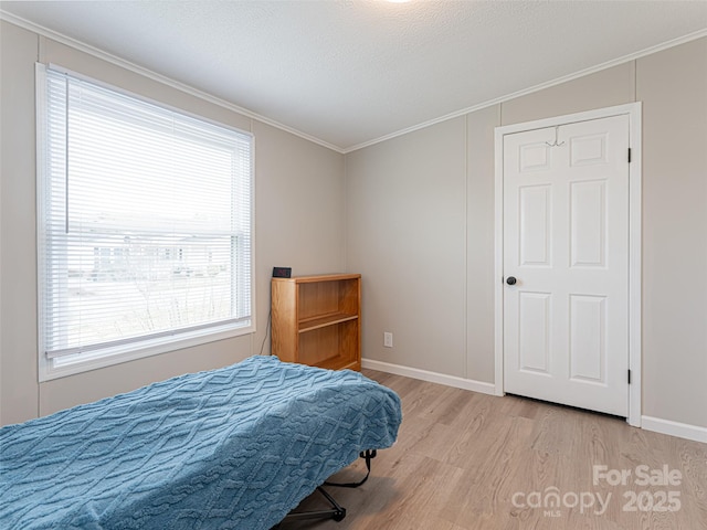 bedroom with a textured ceiling, baseboards, light wood-style floors, and ornamental molding