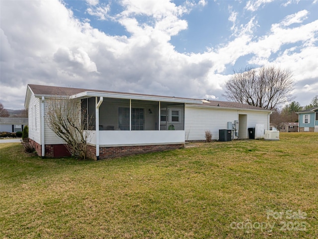 rear view of house featuring a lawn, central AC, and a sunroom