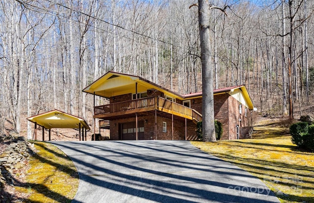 view of front of home with aphalt driveway, brick siding, a front lawn, and a view of trees