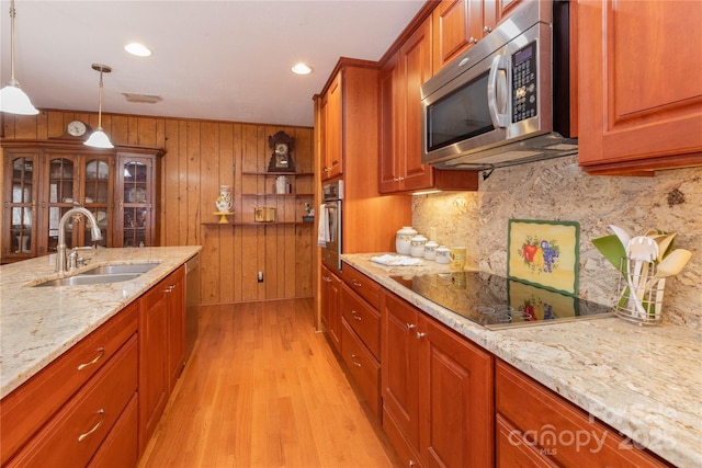 kitchen with stainless steel appliances, a sink, decorative backsplash, light wood finished floors, and brown cabinetry