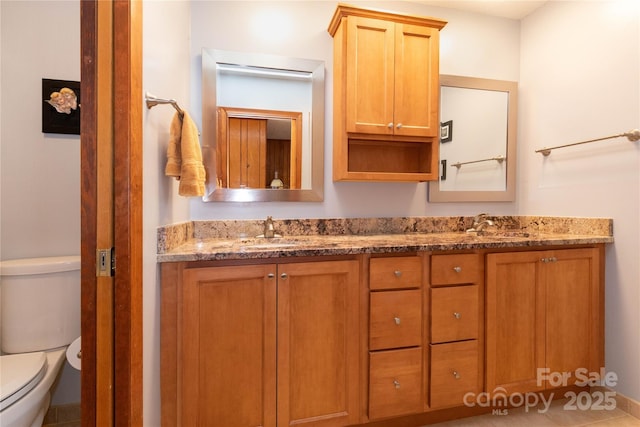 bathroom featuring toilet, double vanity, and a sink