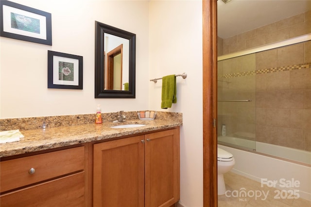 bathroom with toilet, combined bath / shower with glass door, vanity, and tile patterned floors