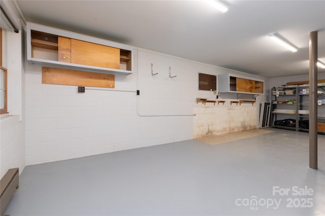 basement with a baseboard heating unit and concrete block wall