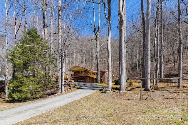 rustic home with driveway and a view of trees