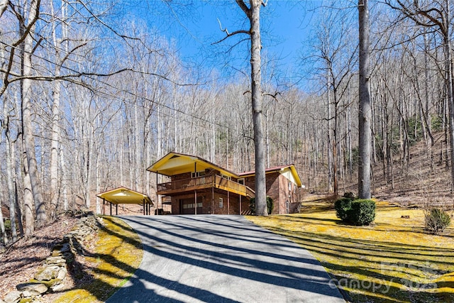 view of front of house with driveway, a front lawn, and a wooded view