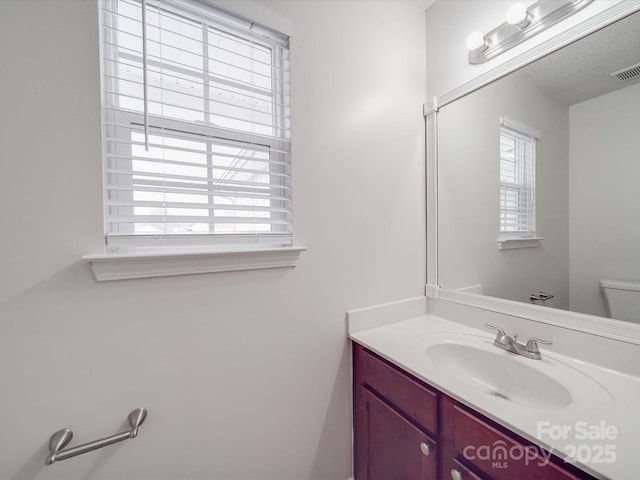 bathroom with visible vents, toilet, and vanity