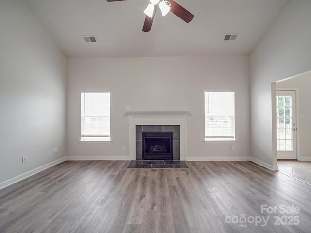 unfurnished living room with a wealth of natural light, visible vents, and a tile fireplace